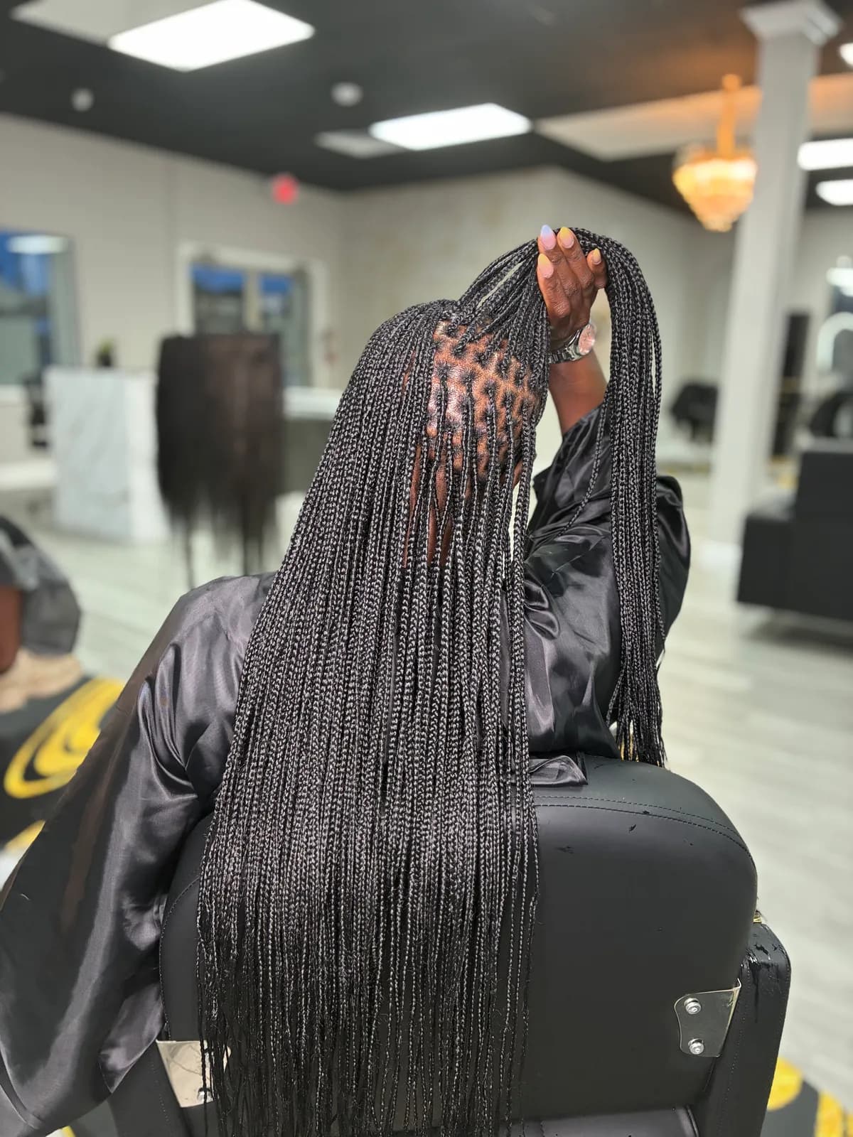 A Milan client showing long black knotless braids and detailed parting
